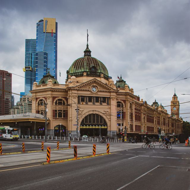 Iconic Flinders Street Station with Melbourne's modern skyline in the background, showcasing urban architecture.